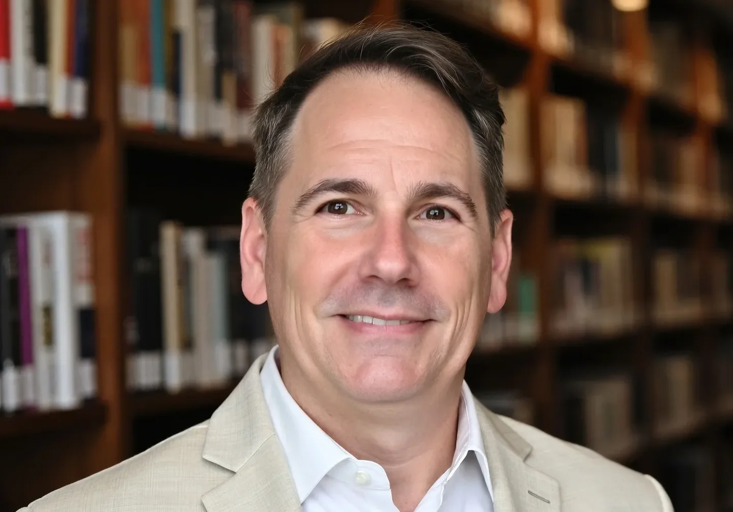 Smiling man wearing beige suit in library